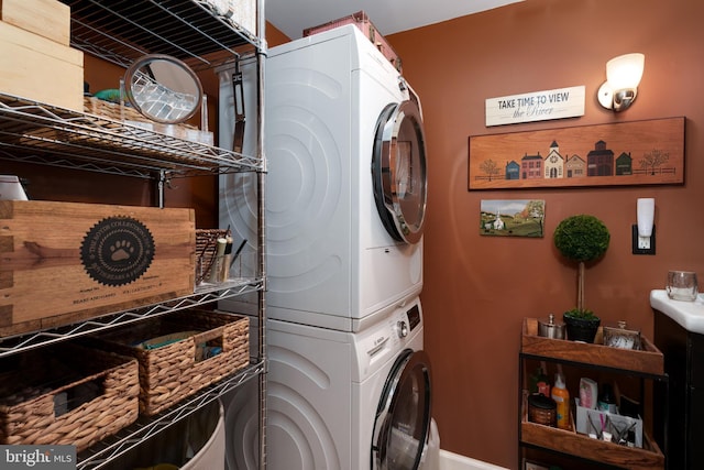 clothes washing area with stacked washer and clothes dryer and baseboards