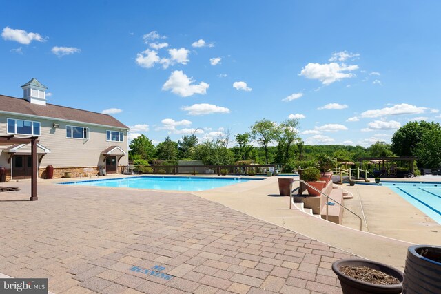 community pool with a patio and fence