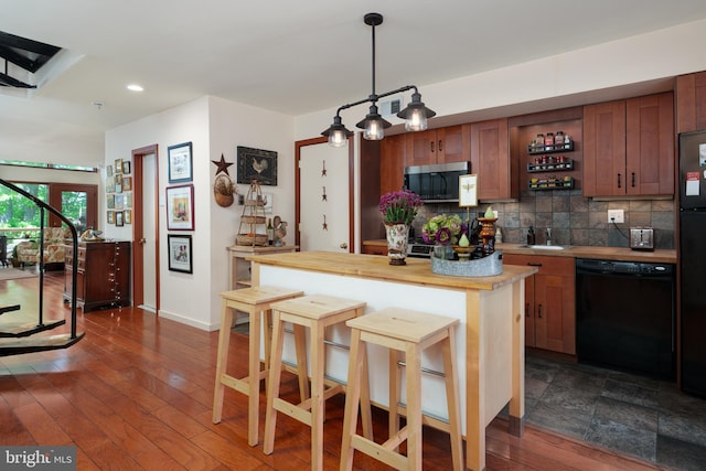 kitchen with black dishwasher, stainless steel microwave, tasteful backsplash, a breakfast bar area, and recessed lighting