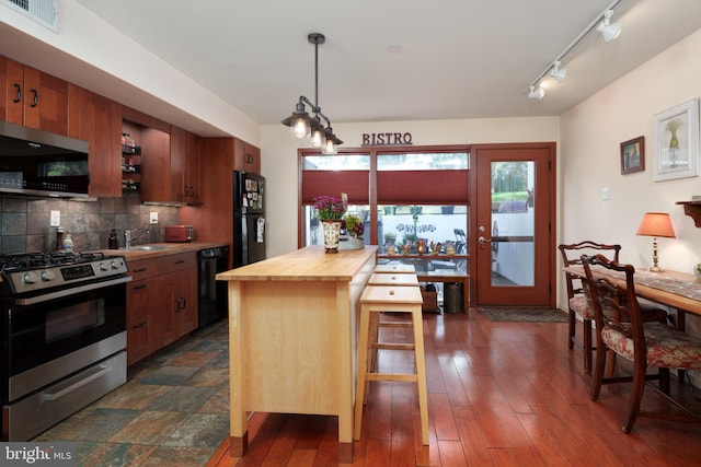 kitchen featuring black appliances, butcher block countertops, backsplash, hanging light fixtures, and track lighting