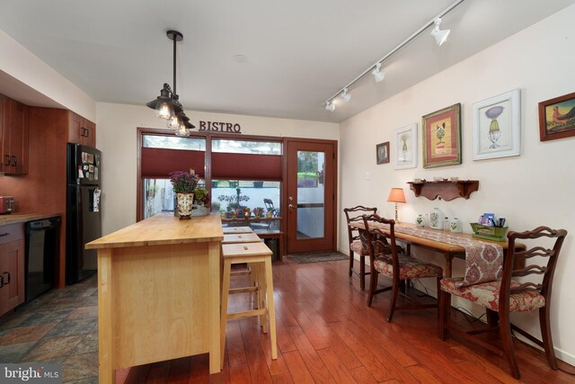 kitchen featuring black appliances, butcher block countertops, track lighting, decorative light fixtures, and dark wood-style flooring