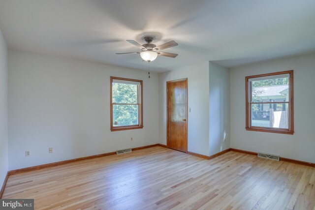 unfurnished room with healthy amount of natural light, light wood-style floors, and baseboards