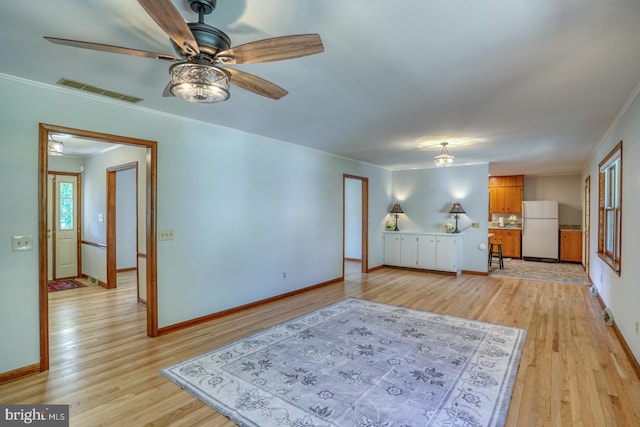 living area featuring light wood-type flooring, ceiling fan, baseboards, and ornamental molding