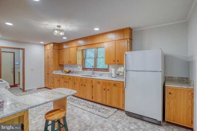 kitchen featuring freestanding refrigerator, light countertops, a sink, recessed lighting, and crown molding