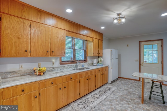 kitchen with freestanding refrigerator, a sink, ornamental molding, recessed lighting, and baseboards