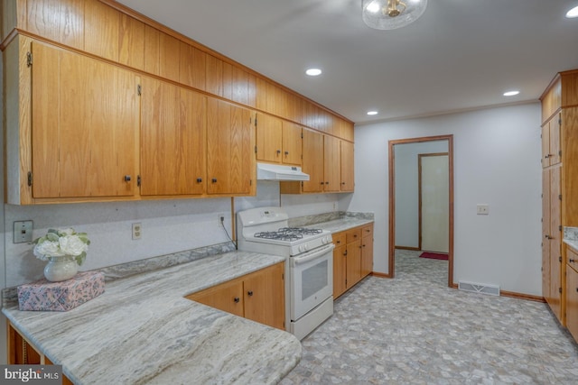 kitchen featuring white gas range, under cabinet range hood, baseboards, light countertops, and recessed lighting