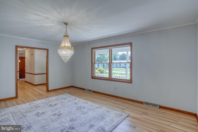 spare room with a chandelier, wood finished floors, baseboards, and ornamental molding