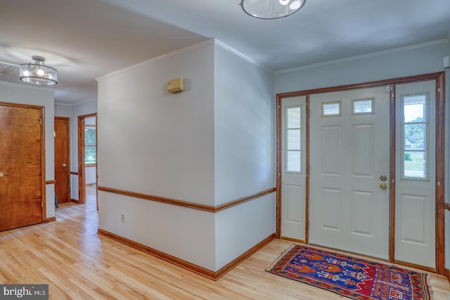 foyer with light wood-style floors, baseboards, and ornamental molding