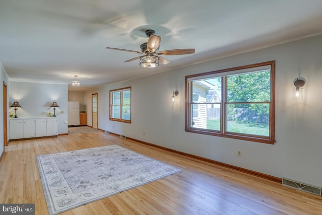 unfurnished living room featuring ceiling fan, baseboards, light wood-style floors, and ornamental molding