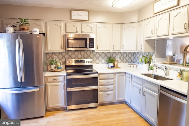 kitchen featuring stainless steel appliances, a sink, light countertops, and decorative backsplash