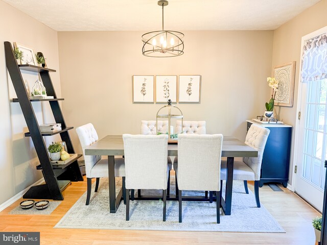 dining area with a chandelier, light wood-type flooring, and baseboards