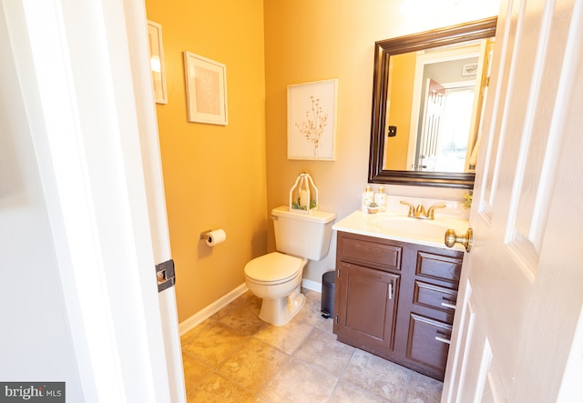 half bath featuring toilet, vanity, tile patterned flooring, and baseboards