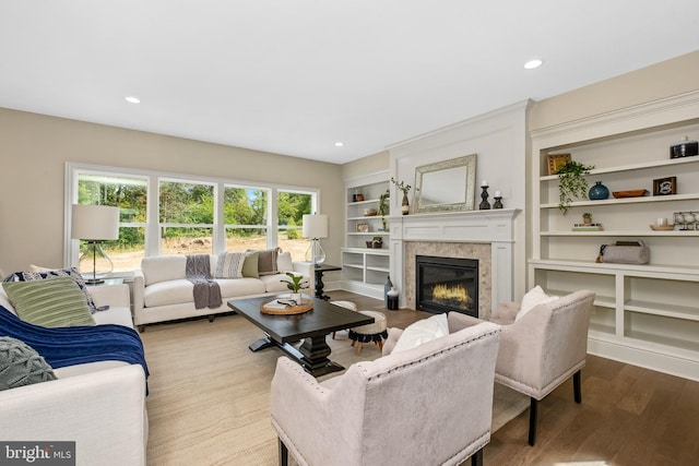 living area featuring a high end fireplace, wood finished floors, built in shelves, and recessed lighting