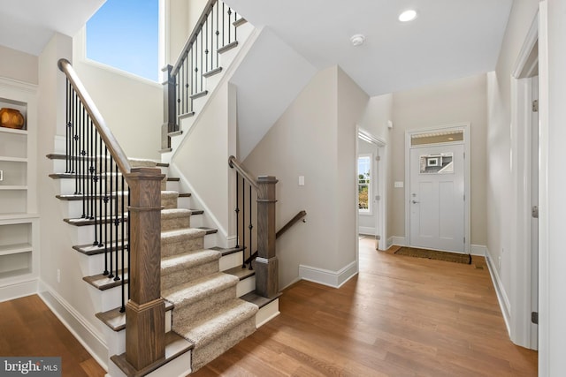 foyer featuring wood finished floors, baseboards, stairway, and recessed lighting