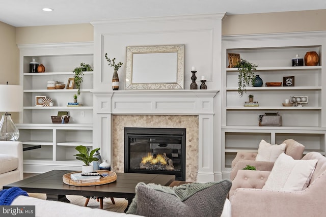 living room with built in shelves, a fireplace, and wood finished floors