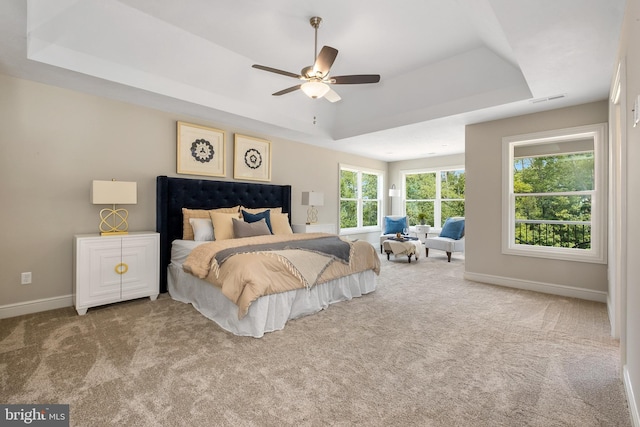 bedroom featuring a raised ceiling, carpet flooring, baseboards, and a ceiling fan