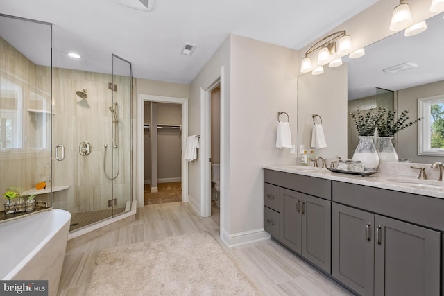 bathroom featuring a shower stall, double vanity, a soaking tub, and baseboards
