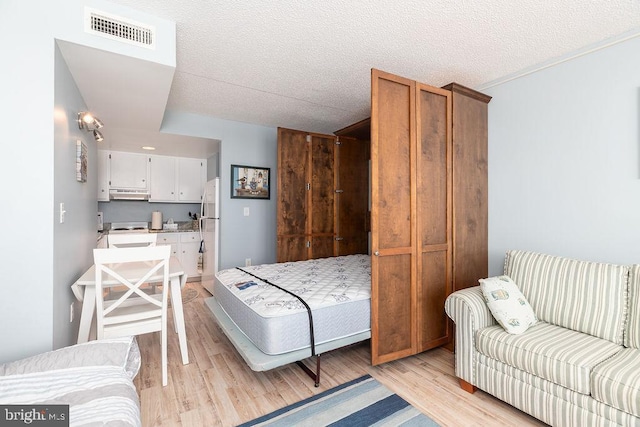10900 Coastal Hwy Unit 805, Ocean City, MD 21842 - bedroom featuring freestanding refrigerator, light wood-type flooring, and a textured ceiling