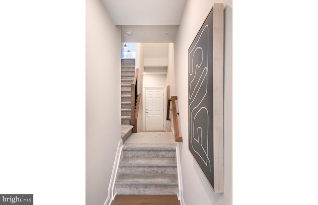staircase featuring baseboards and wood finished floors