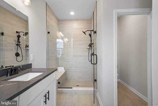 bathroom featuring a stall shower, vanity, recessed lighting, baseboards, and wood finished floors