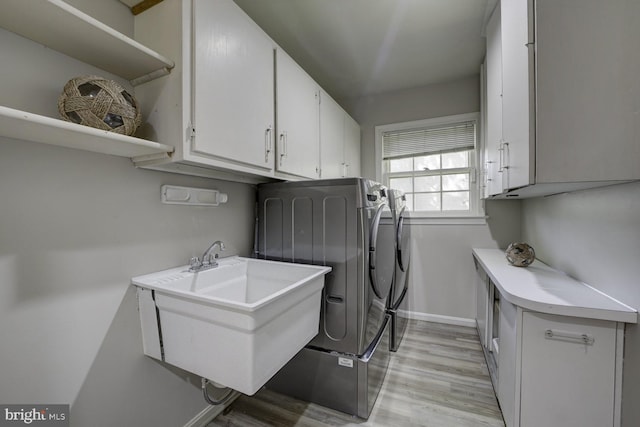10013 Ormond Rd, Potomac, MD 20854 - laundry area with washer and dryer, cabinet space, light wood-type flooring, and baseboards