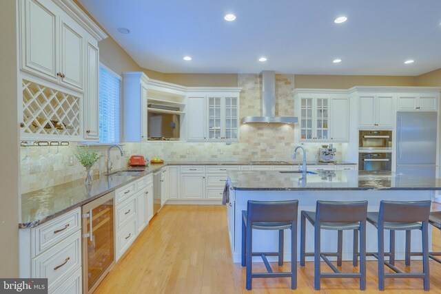829 Golden Arrow St, Great Falls, VA 22066 - kitchen with wall chimney range hood, a sink, beverage cooler, a kitchen breakfast bar, and recessed lighting