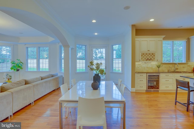 829 Golden Arrow St, Great Falls, VA 22066 - dining area featuring wine cooler, crown molding, arched walkways, light wood finished floors, and recessed lighting