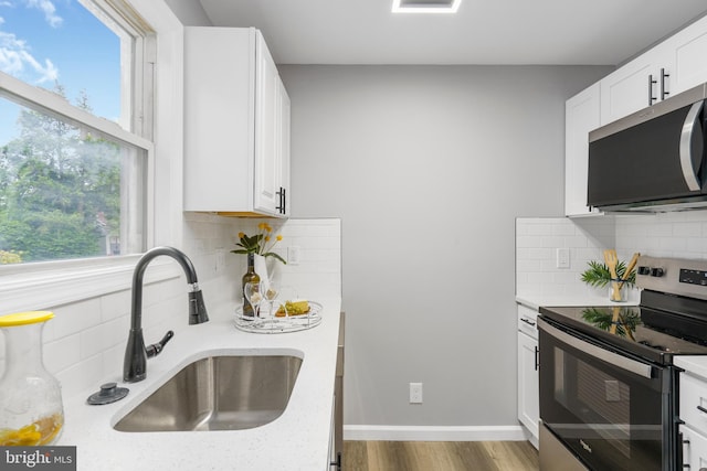 3531 Milford Mill Rd, Baltimore, MD 21244 - kitchen featuring stainless steel appliances, a sink, tasteful backsplash, white cabinets, and wood finished floors