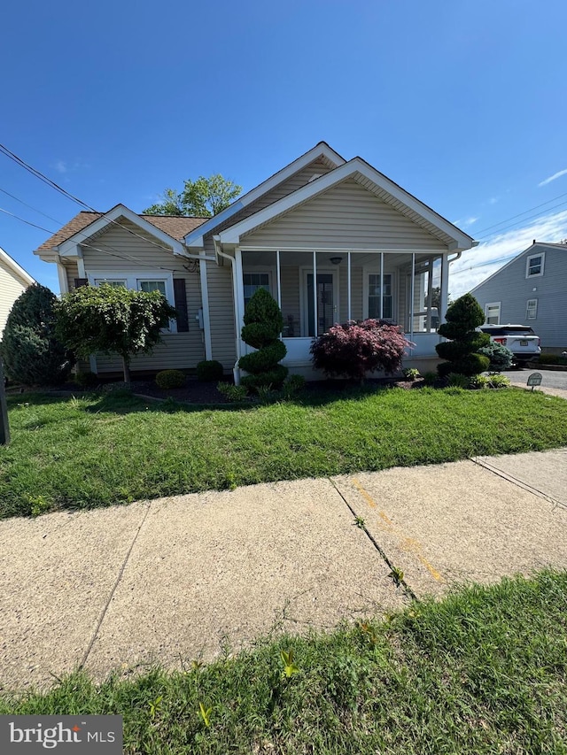 view of front of house with a sunroom and a front yard
