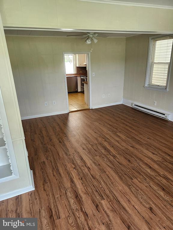 unfurnished room with a baseboard radiator, wood finished floors, a ceiling fan, and baseboards