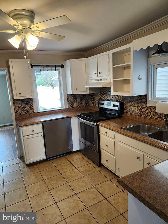 kitchen with appliances with stainless steel finishes, crown molding, a sink, healthy amount of natural light, and open shelves