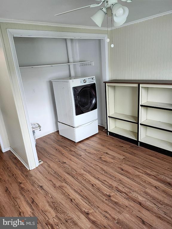 clothes washing area featuring washer / clothes dryer, wood finished floors, ornamental molding, and ceiling fan