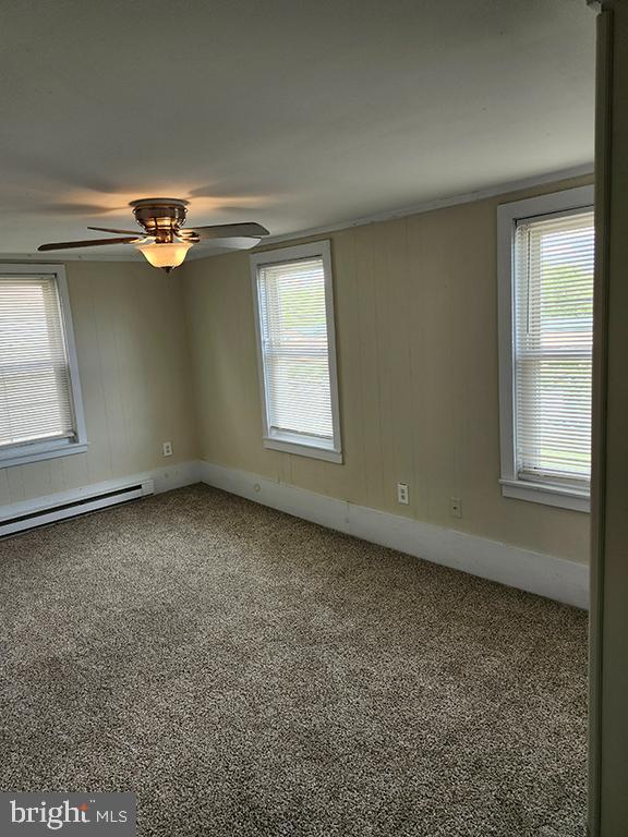 unfurnished room featuring a baseboard radiator, healthy amount of natural light, and carpet flooring