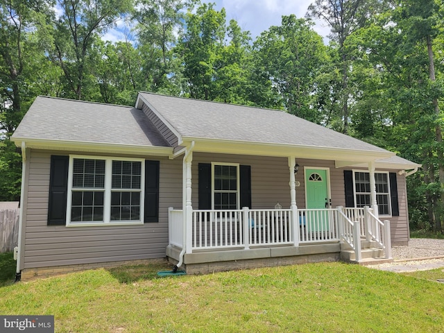ranch-style home featuring covered porch, a front lawn, and a shingled roof