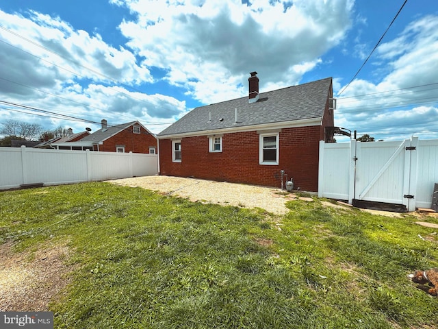 106 Killoran Dr, New Castle, DE 19720 - rear view of house featuring a gate, brick siding, a chimney, a patio area, and roof with shingles