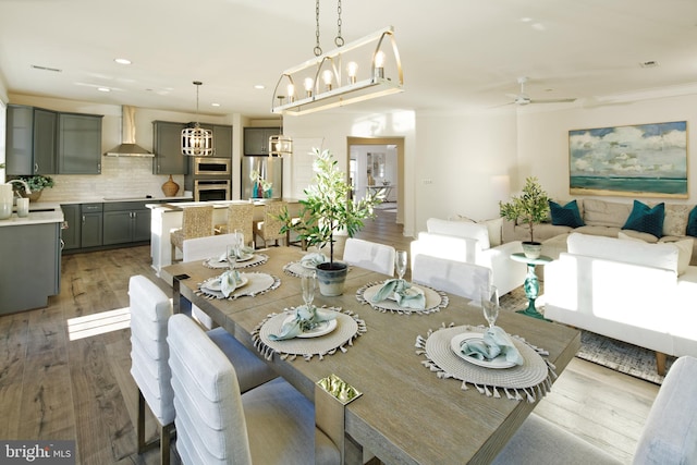 dining room with recessed lighting, wood finished floors, a ceiling fan, ornamental molding, and a chandelier