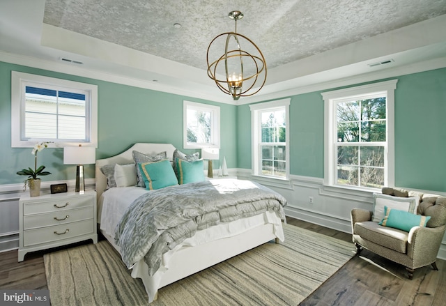 bedroom featuring a chandelier, wood finished floors, a raised ceiling, and wainscoting
