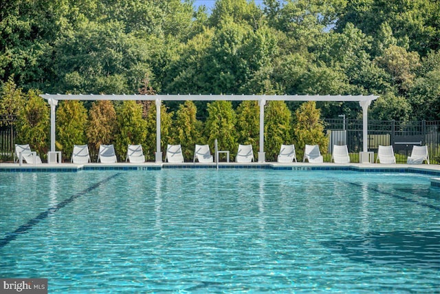 community pool featuring fence and a wooded view