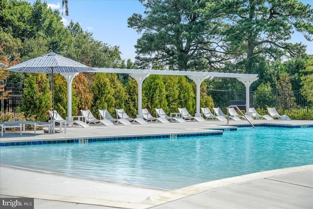community pool with fence, view of wooded area, and a patio