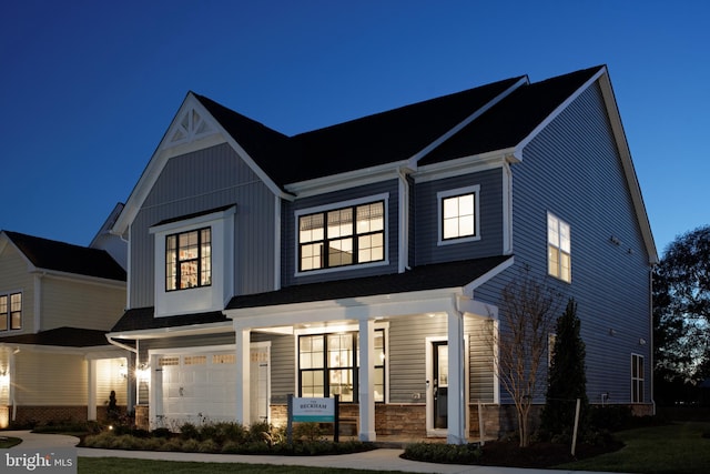 view of front of home with a porch, an attached garage, and stone siding