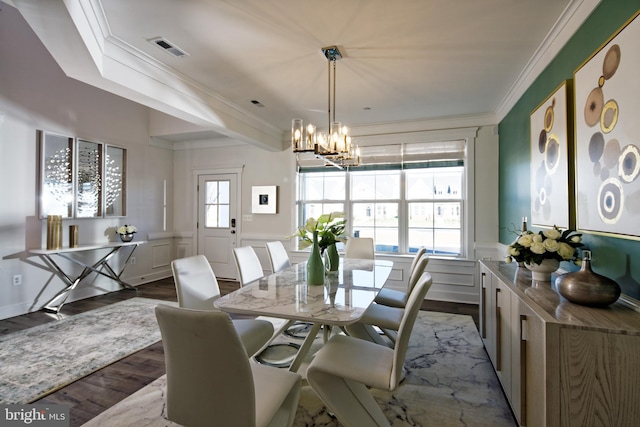 dining space with dark wood finished floors, ornamental molding, a chandelier, a wainscoted wall, and a decorative wall