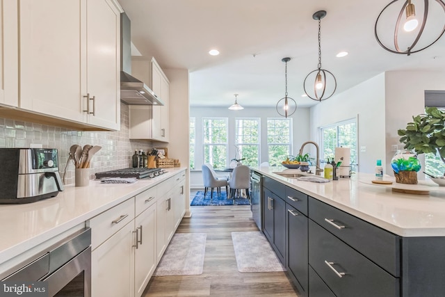 kitchen with a sink, white cabinets, light countertops, light wood-style flooring, and tasteful backsplash