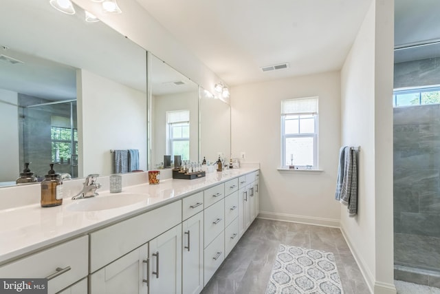 full bathroom with tiled shower, double vanity, baseboards, and marble look tile flooring