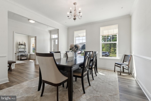 dining room with a chandelier, wood finished floors, crown molding, and baseboards