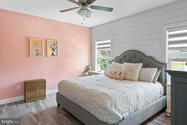 22378 Mahogany Rd, Milton, DE 19968 - bedroom with multiple windows, baseboards, wood finished floors, wood walls, and ceiling fan