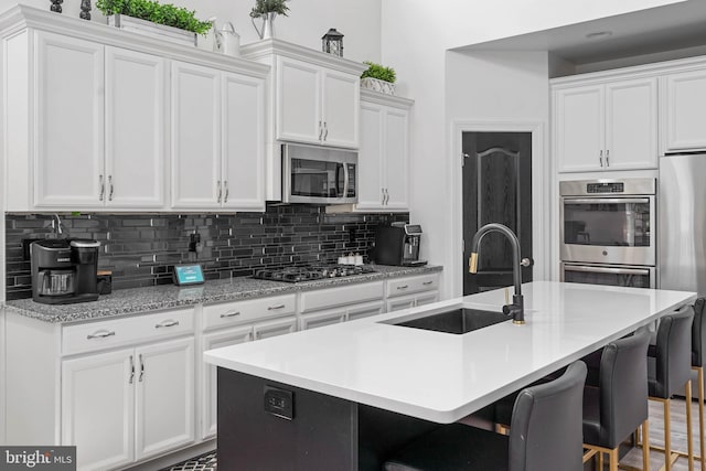 22378 Mahogany Rd, Milton, DE 19968 - kitchen with a sink, stainless steel appliances, backsplash, white cabinetry, and light countertops
