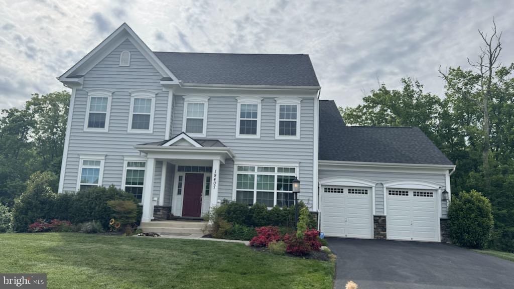 view of front facade with an attached garage, asphalt driveway, a front yard, and a shingled roof