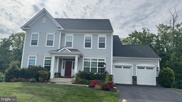 view of front facade with an attached garage, asphalt driveway, a front yard, and a shingled roof