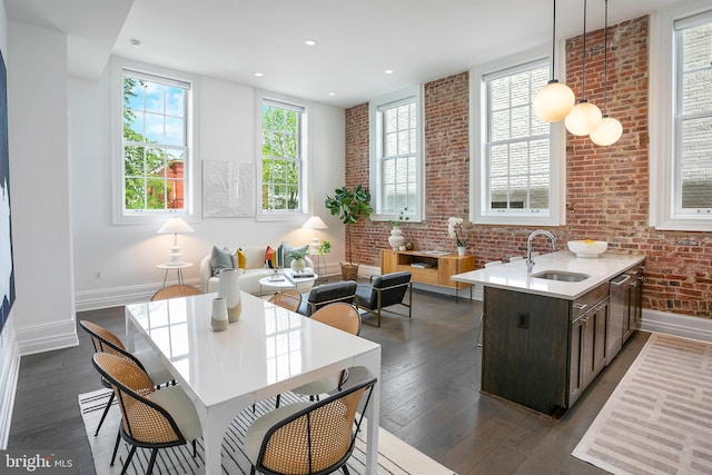 kitchen featuring a sink, baseboards, dark wood-style floors, light countertops, and brick wall