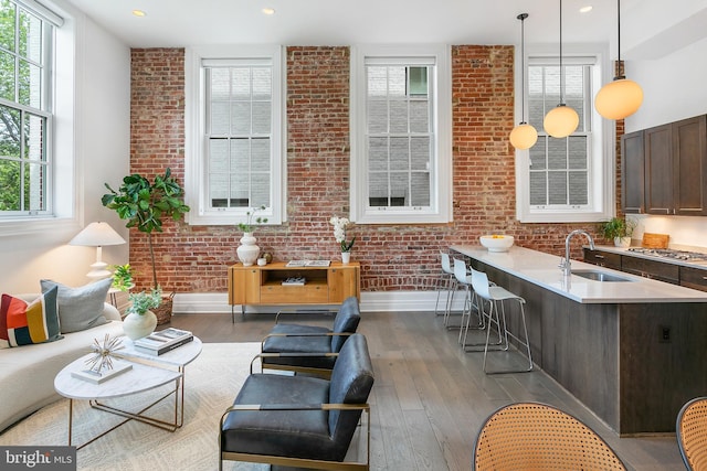 living area with plenty of natural light, hardwood / wood-style floors, and brick wall